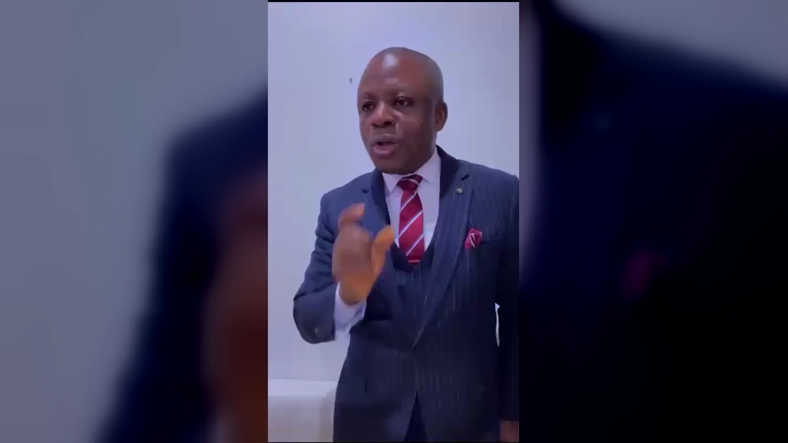 Kufre Okon teaching to camera in a pinstripe suit, at the start of Identity of the Church, episode one.