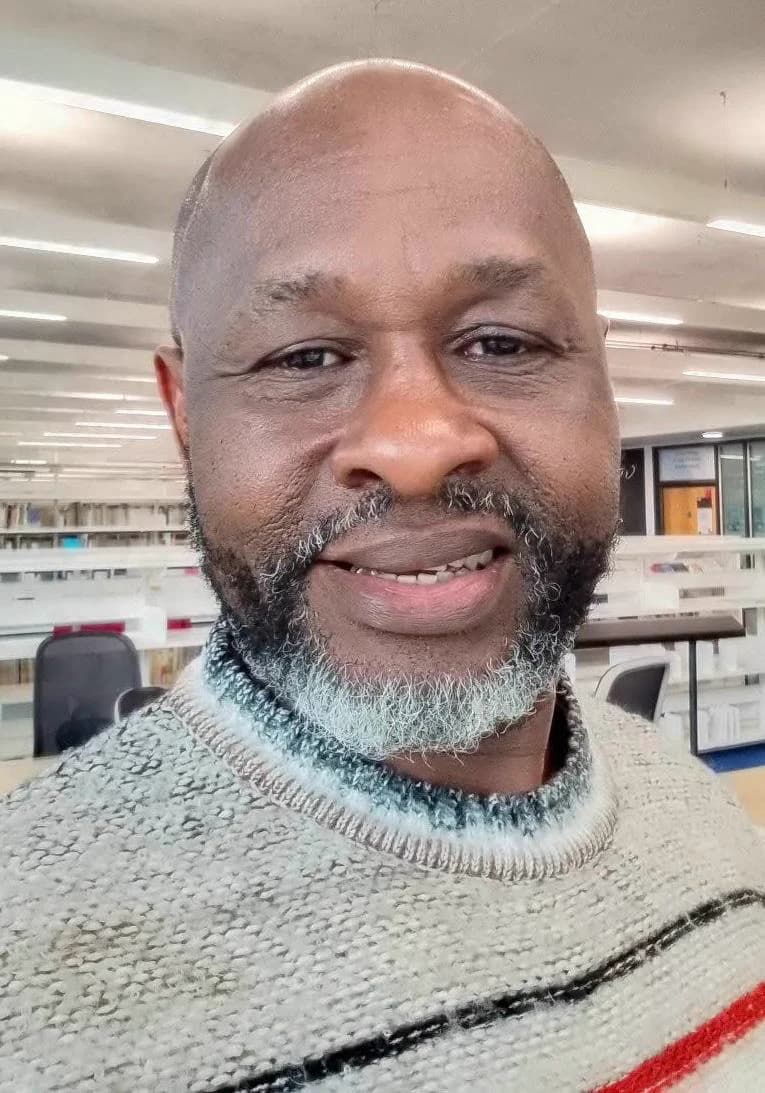 Kabnim Akpabio, Trustee and Media Lead, smiling in a library.