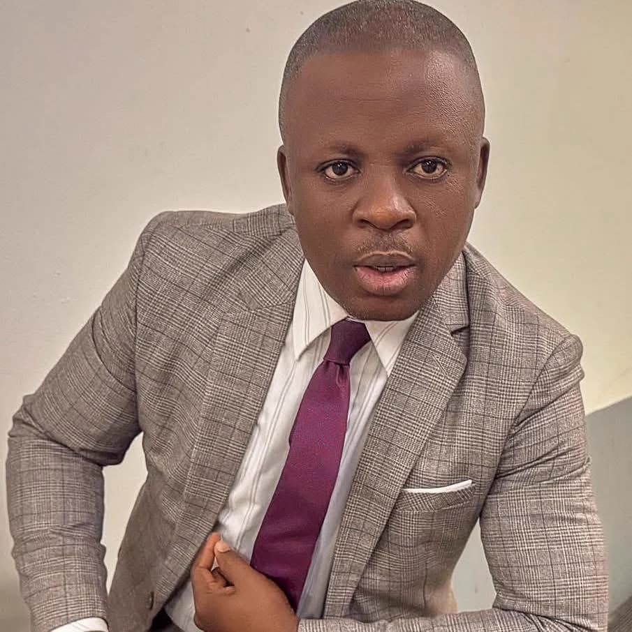 Kufre Okon, Resident Minister, in a grey check suit and maroon tie, looking to camera.